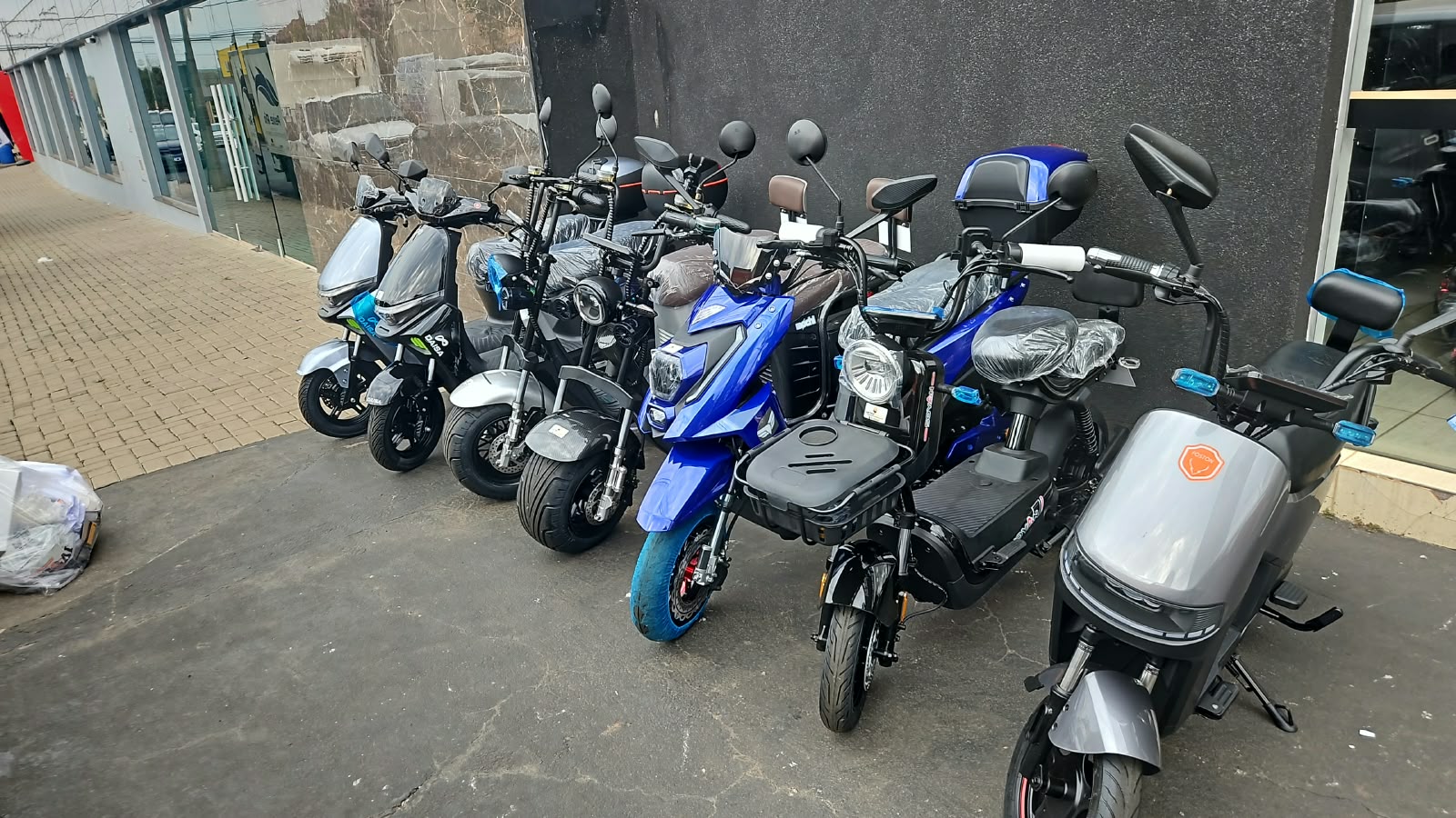 Motos e scooters elétricas enfileiradas na calçada da loja